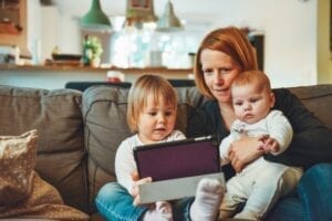 alt="woman sitting on a sofa with two kids"